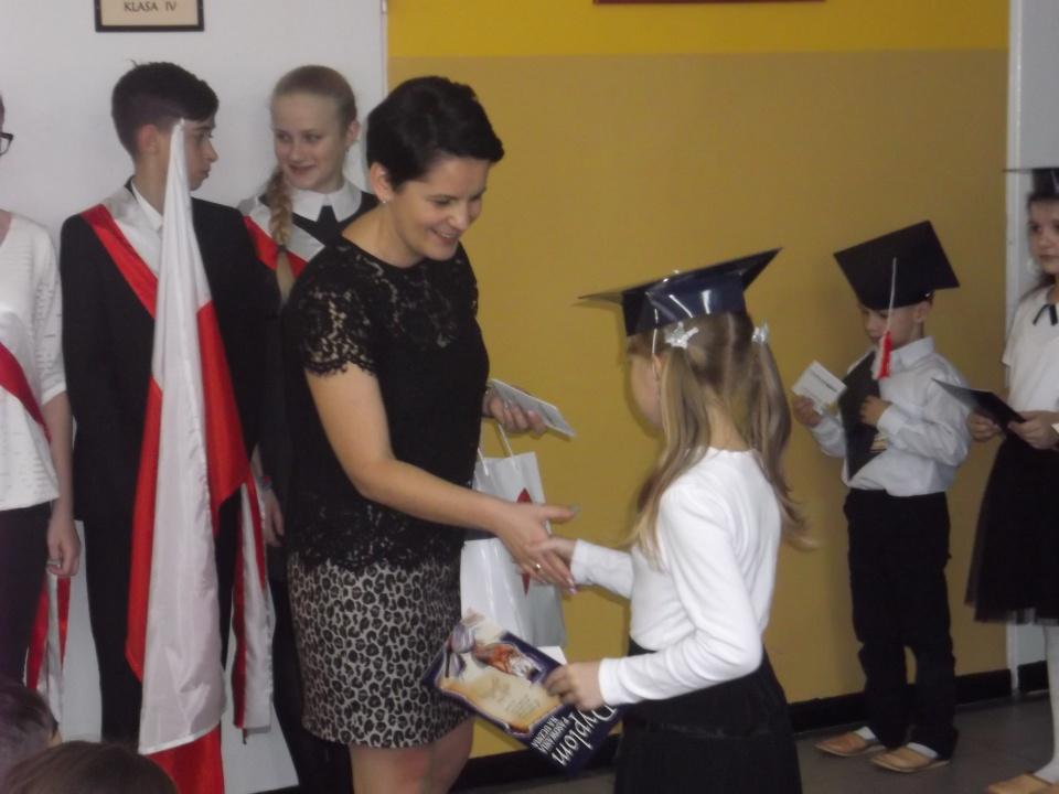 Ślubowanie klasy I -  opiekun SKO z BS w Wąsewie wręcza książeczki uczniom klasy I